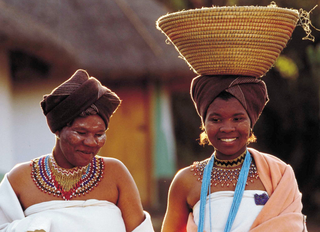 A Xhosa bride walks alongside an older woman in Lesedi Cultural Village in South Africa